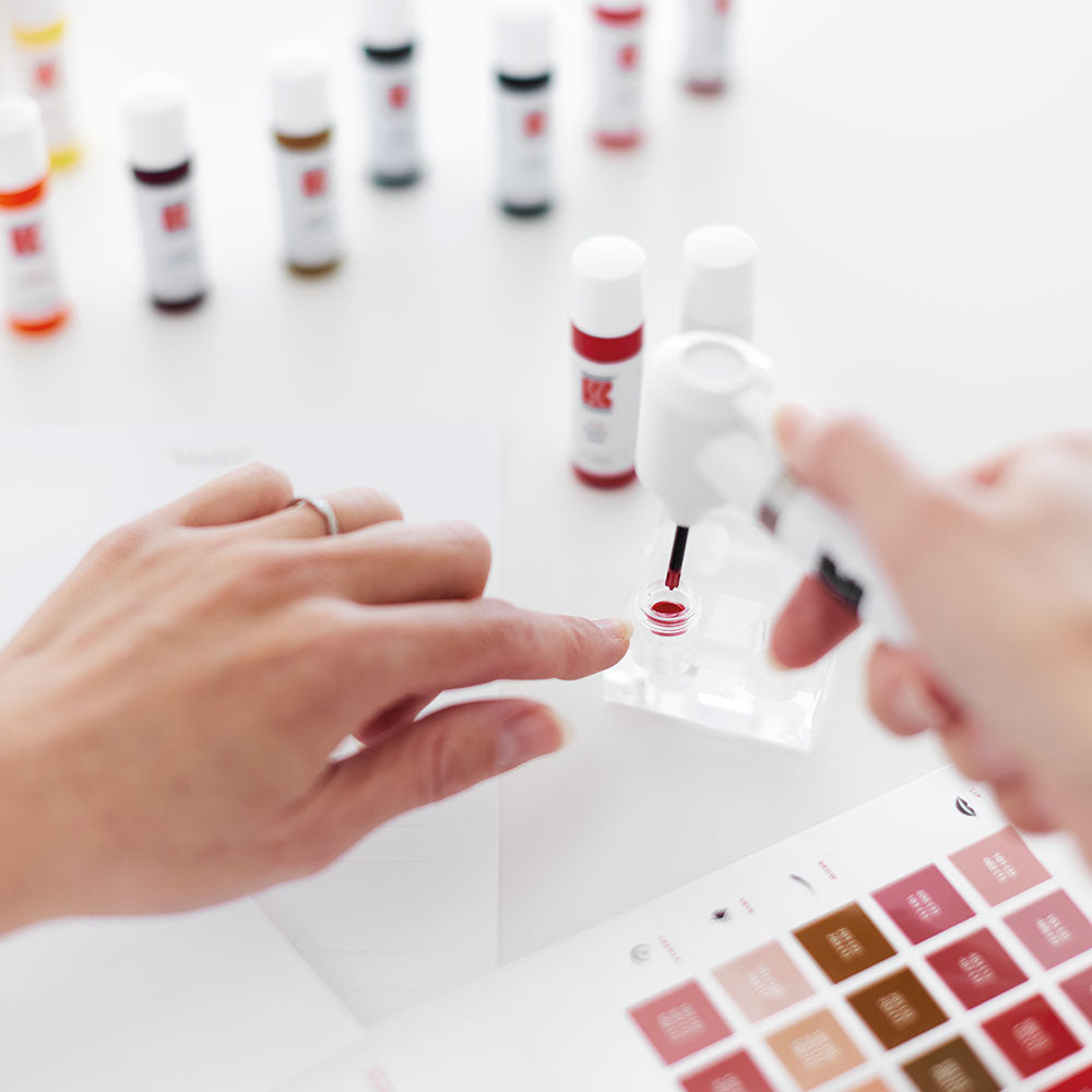 PMU artist testing and labeling Swiss Color® pigment shades on a color swatch card – precision mixing and tone control for brows and lips